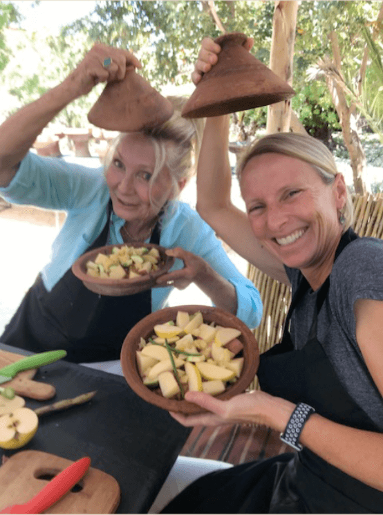 2 women holding tagines over their heads laughing